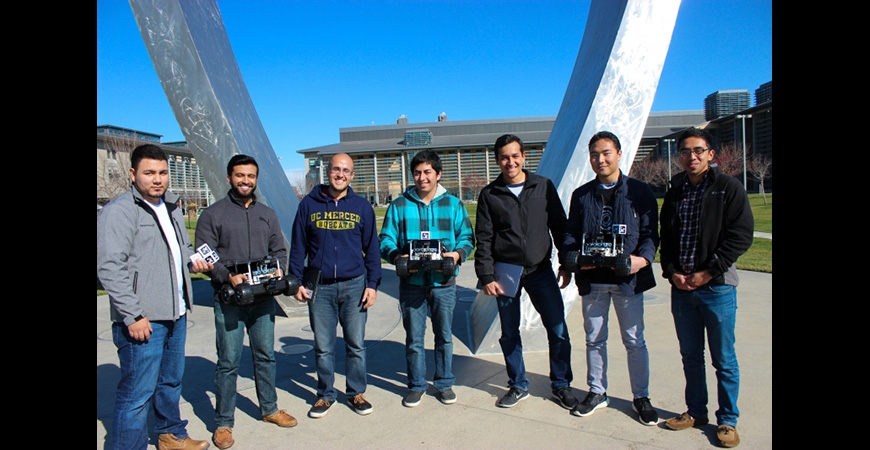 group of students taking a picture in front of the beginnings sculpture